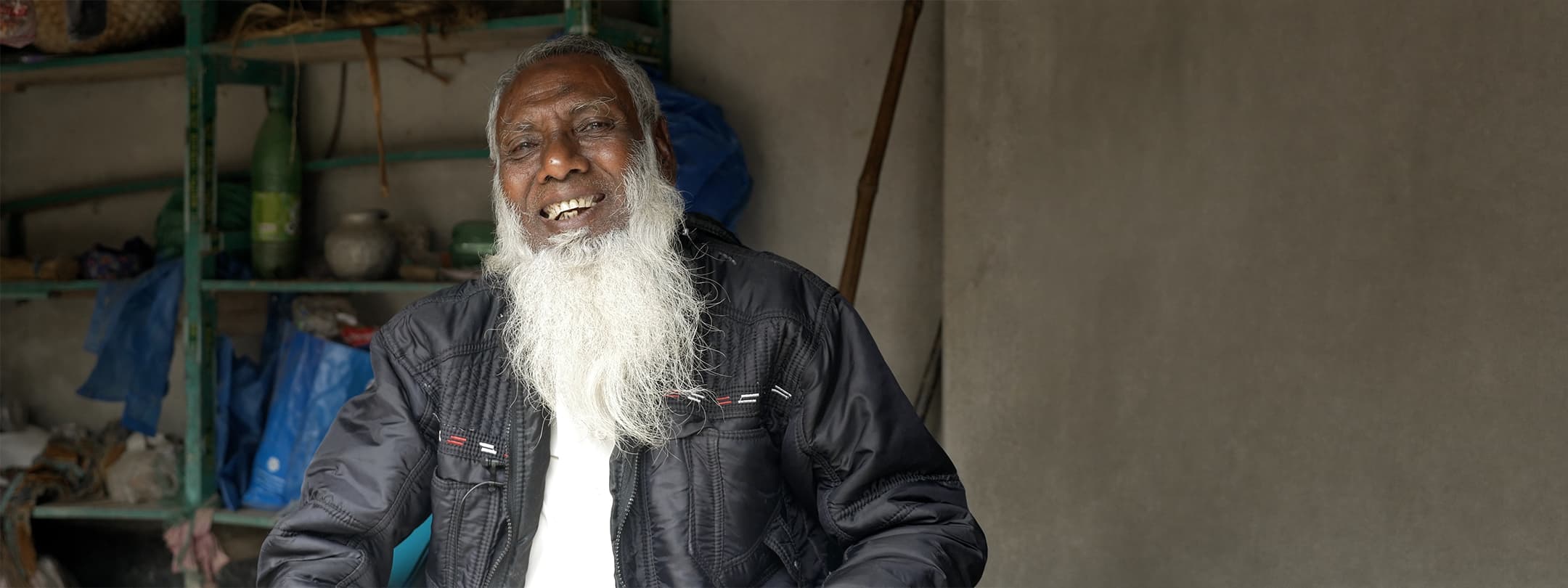 An elderly man with a long white beard smiling warmly