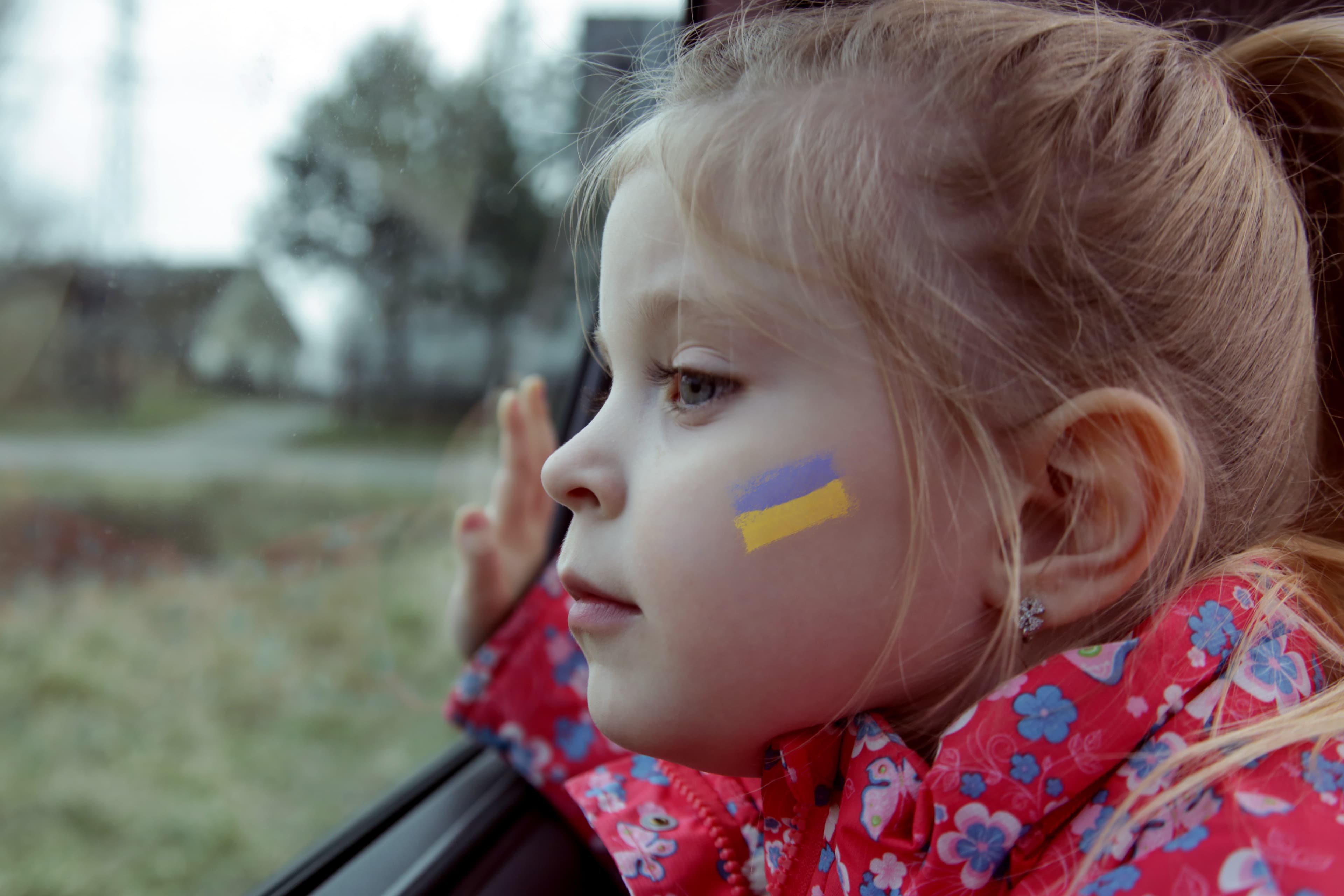 A young girl with the Ukrainian flag painted on her cheek