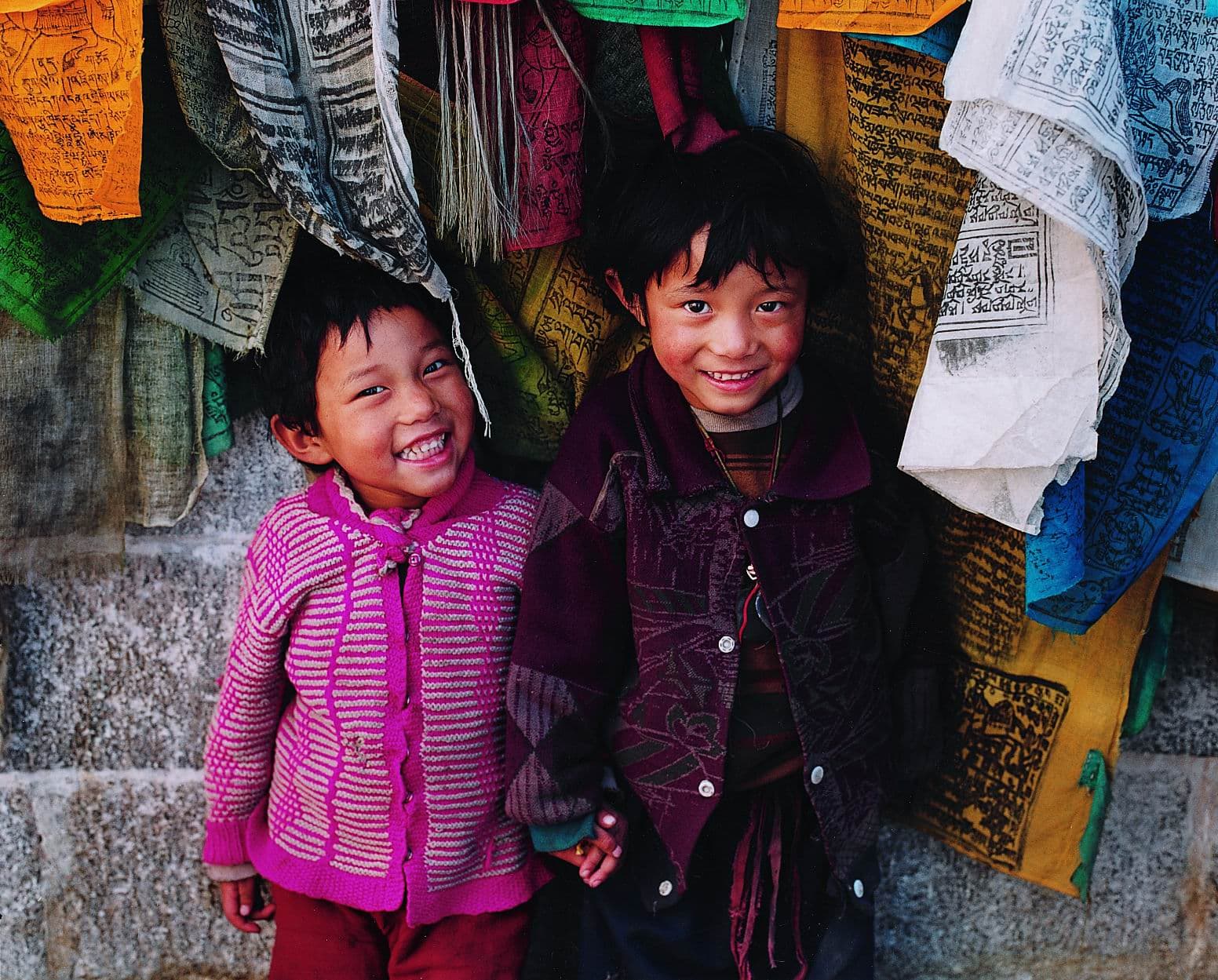 Two boys in front of Tibetan prayer flags
